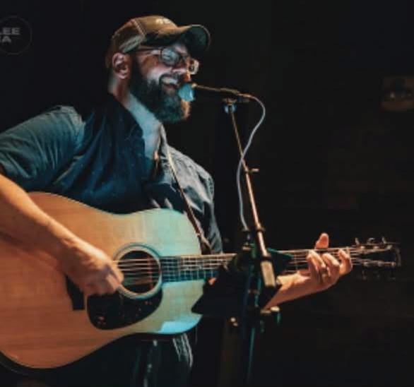 Photo of Bret Maynard holding a guitar